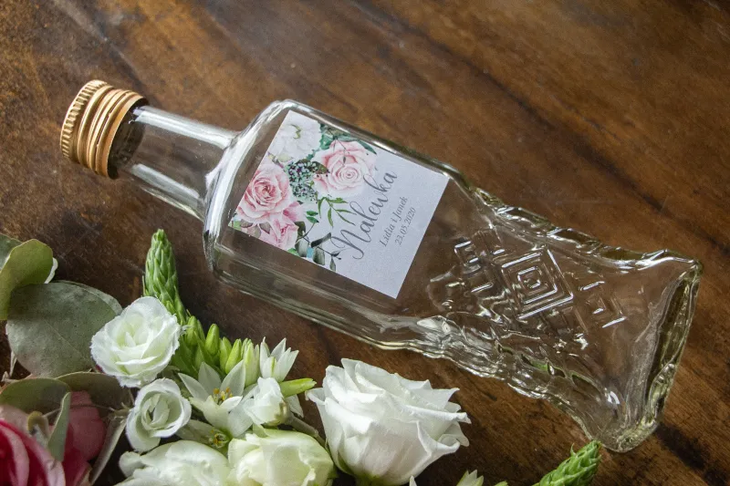 Ślubne Butelki na nalewki z etykietą w kolorze szarym z kompozycją z białych i pastelowych róż