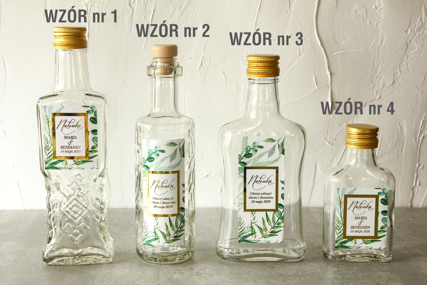 Bottiglie per liquori con etichetta in stile glamour, cornice dorata, testo e motivo botanico greenery