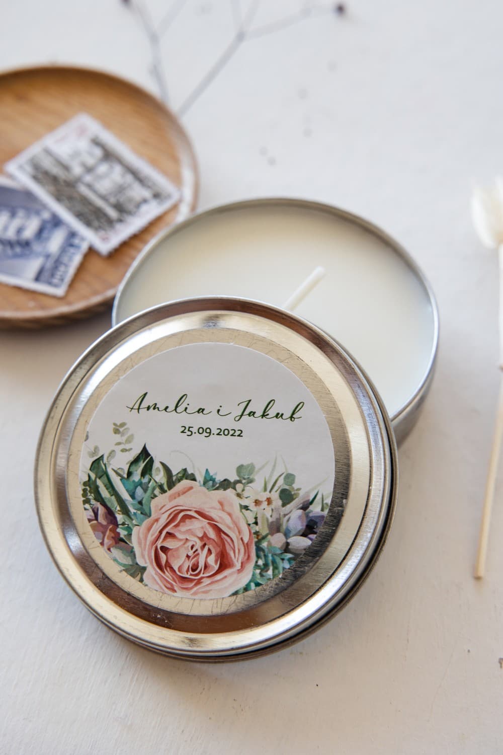 Candele nuziali rotonde come bomboniere per ospiti. Etichetta con peonie rosa e foglie verdi