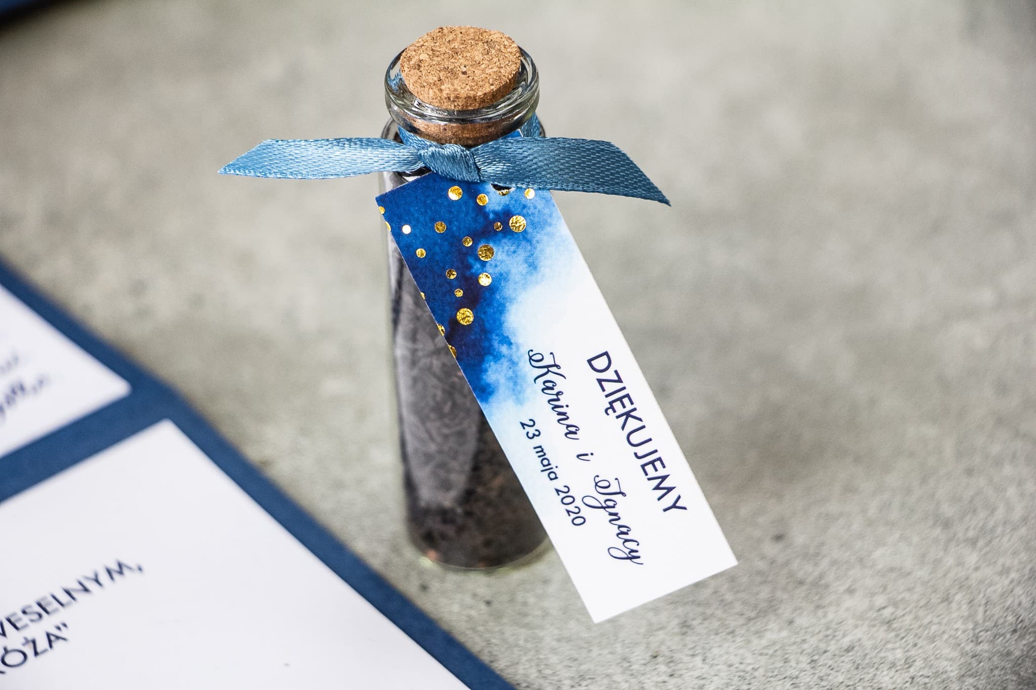 Remerciements pour les invités sous forme de fioles de thé. Étiquette bleu marine avec pois dorés