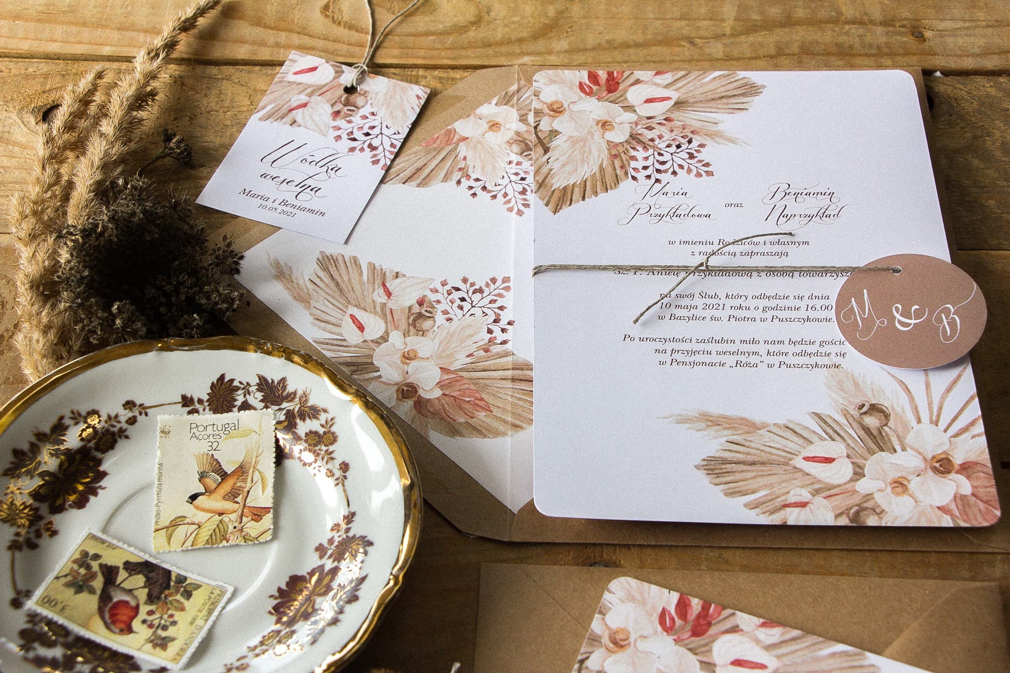 Detalle de invitación de boda boho con diseño de hierba pampas y sobre kraft.