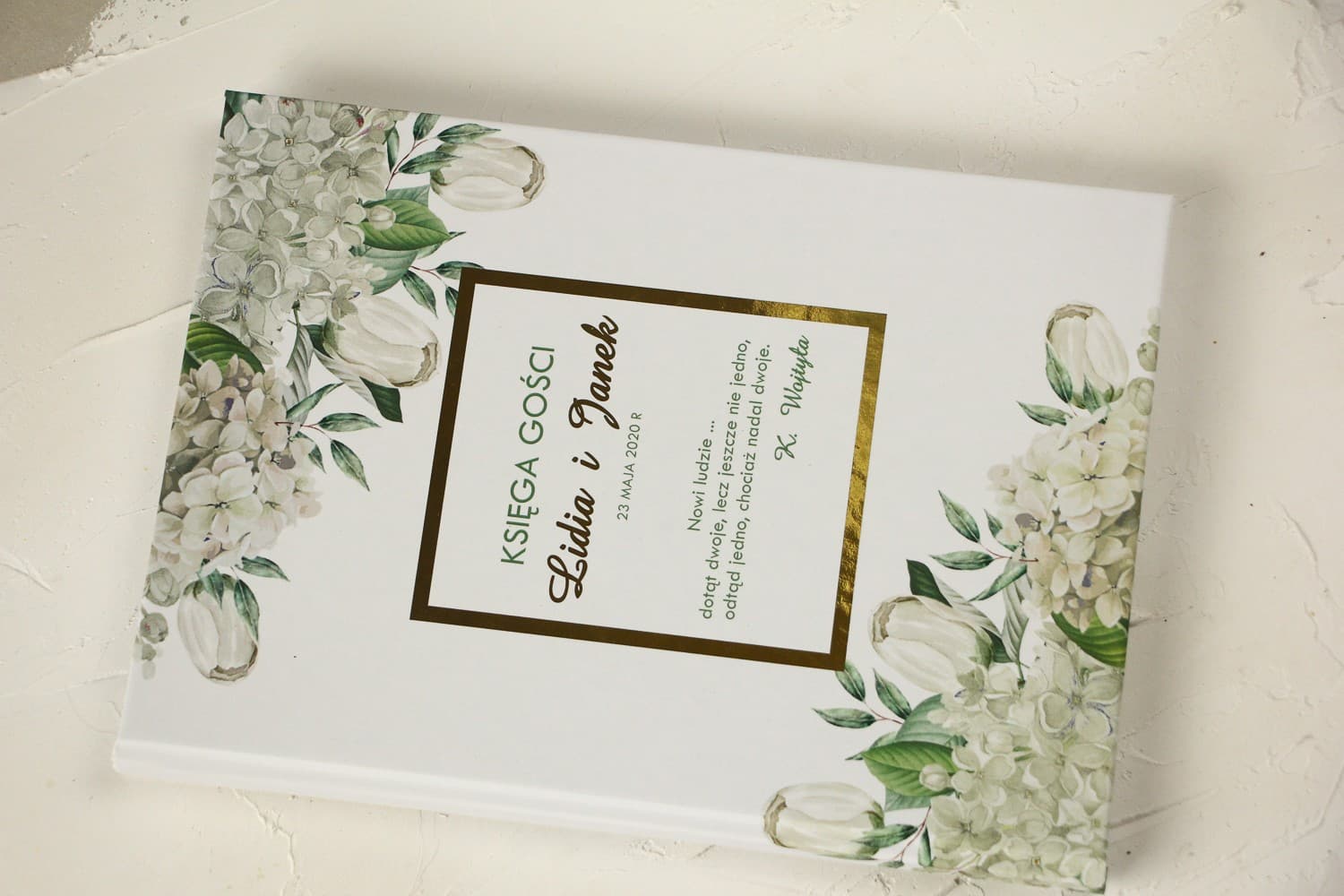 Livre d'or de mariage avec dorures, hortensia blanc et tulipes dans un écrin de verdure
