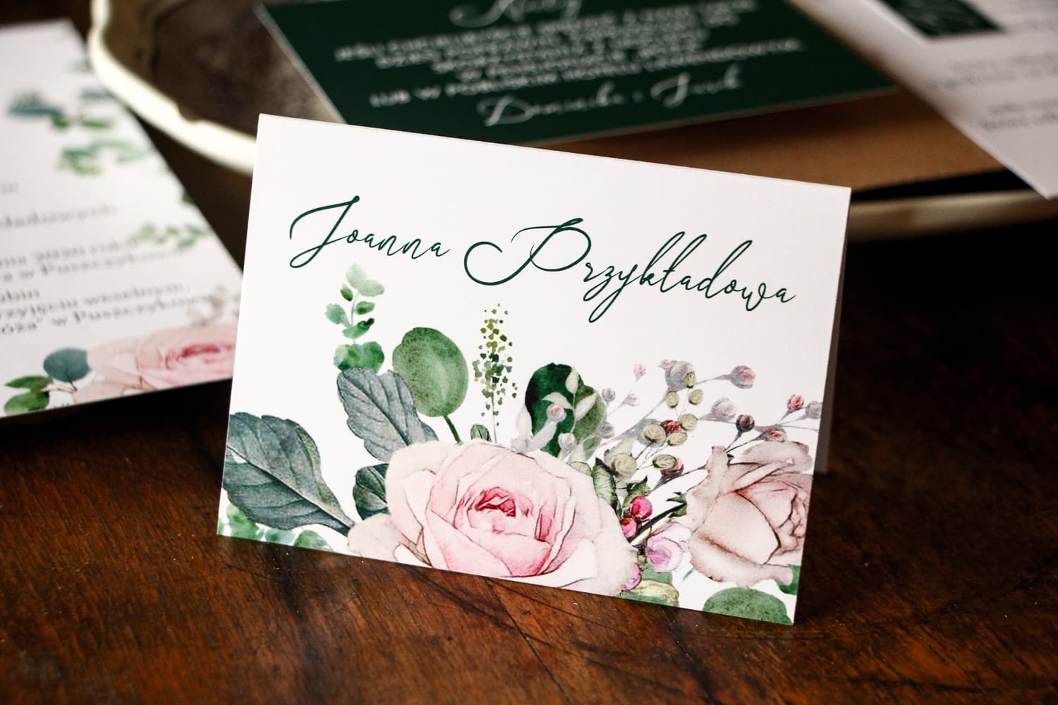 Marcasitios de boda con rosas y ramas verdes de eucalipto sobre papel premium