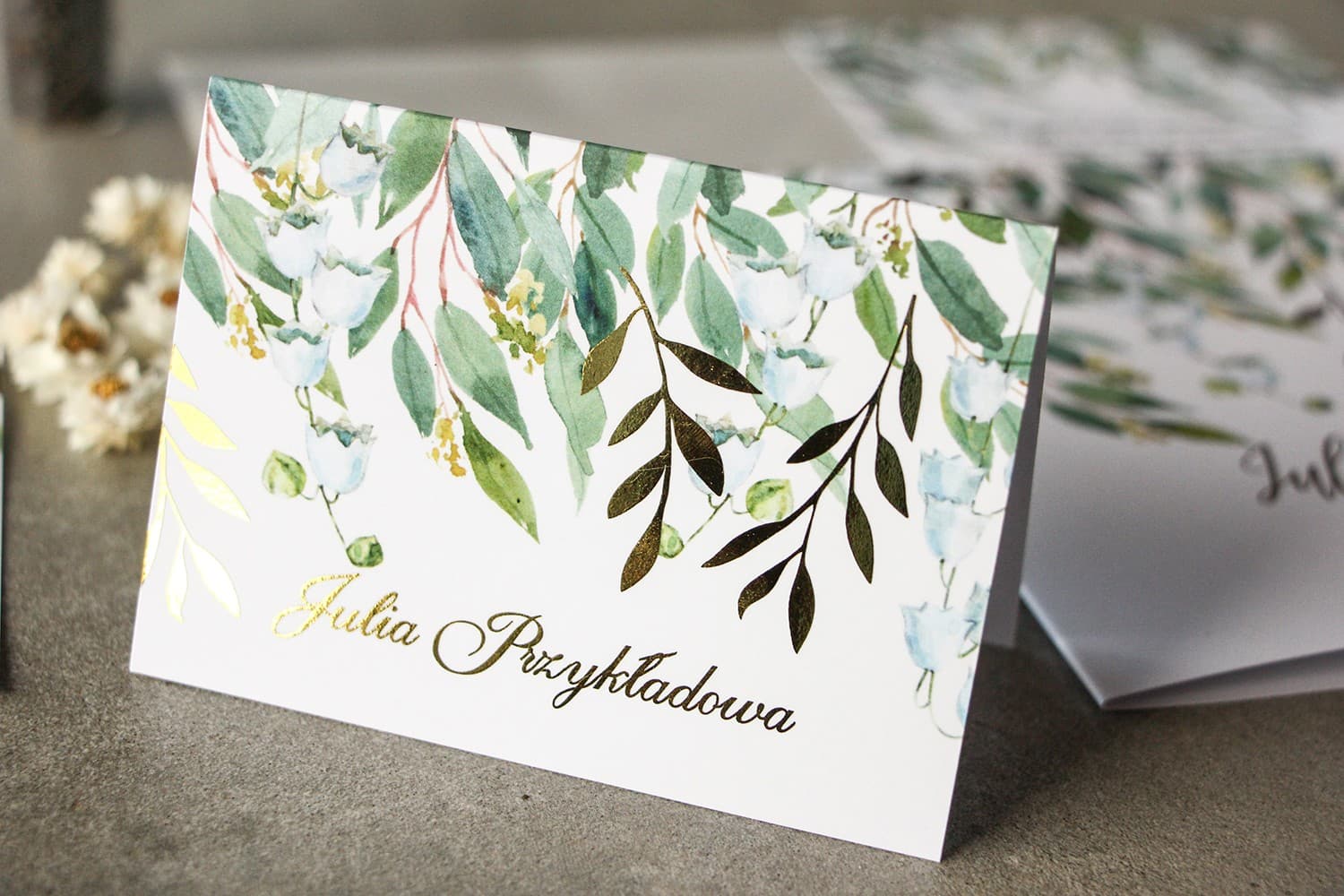 Marcasitios de boda en blanco y verde con lirios del valle y ramas doradas estilo glamour