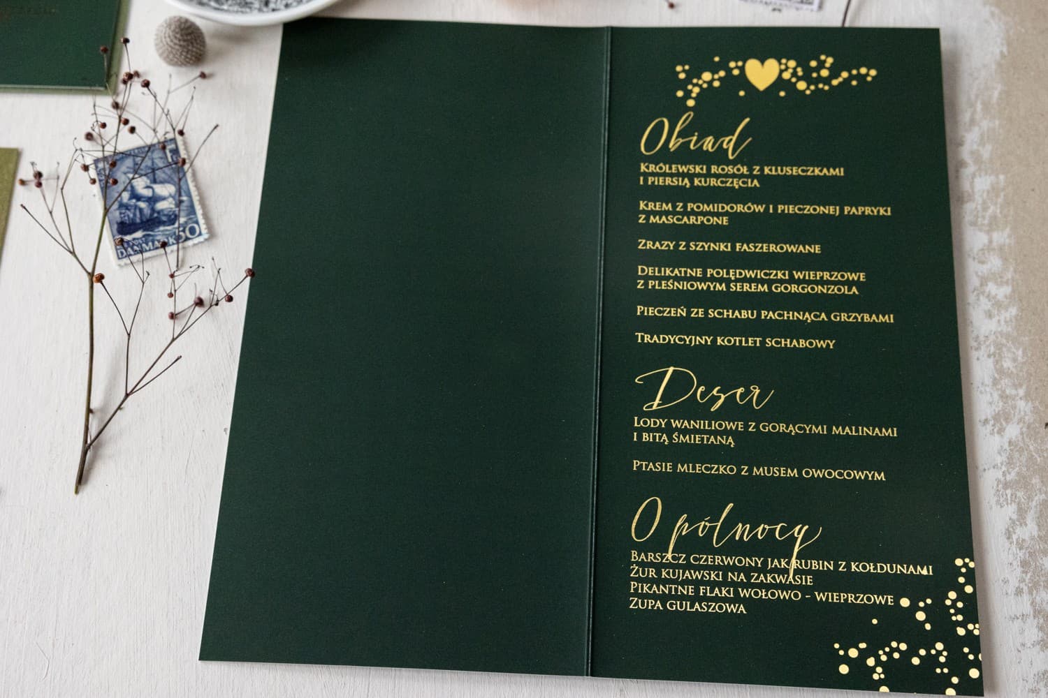 Detalle del menú de boda verde y oro con motivo celestial de estrellas.
