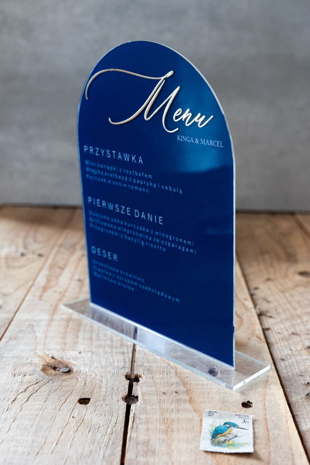 Detalle de menú de boda en metacrilato azul marino y letras doradas