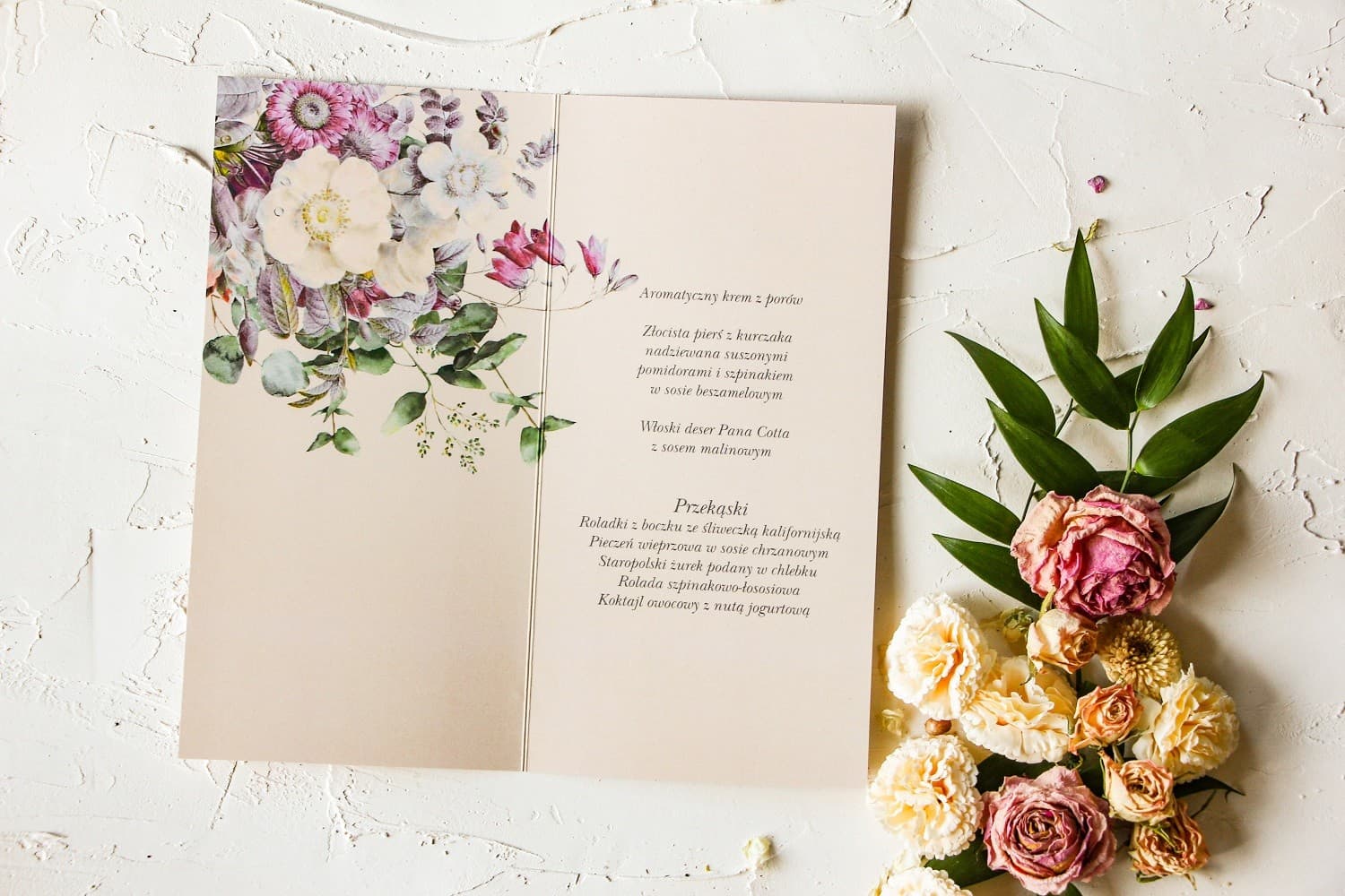 Menú de boda elegante con flores pastel y detalles en plata sobre papel crema