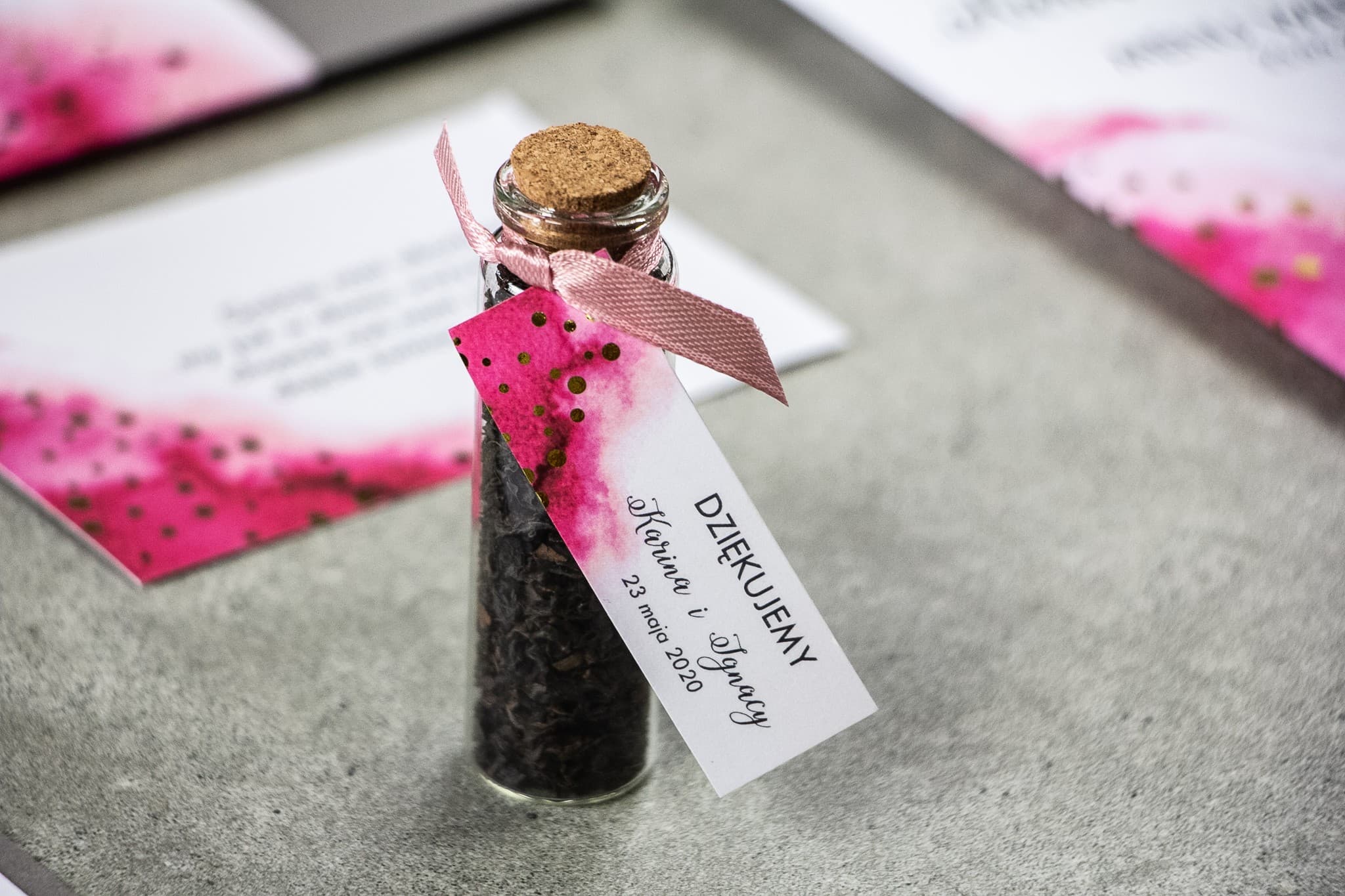 Gastgeschenke in Form von Tee-Fläschchen mit rosa Anhänger und Goldpunkten