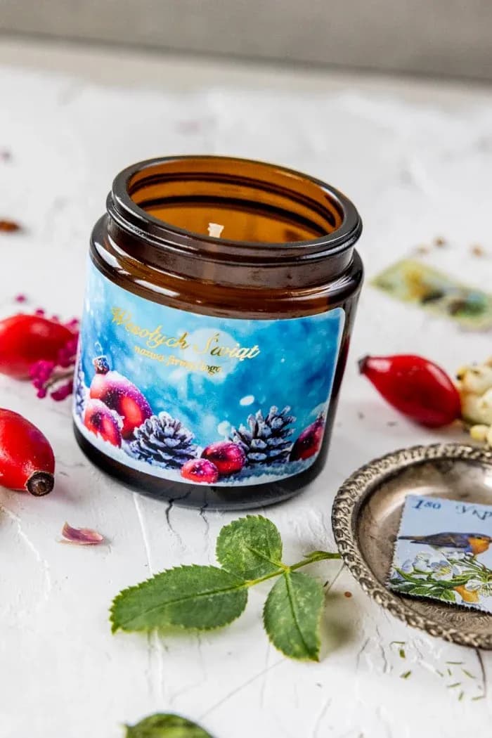 Candela soia con grafica pigne e bacche SE2 Candela di soia in vasetto marrone con grafica artistica invernale dipinta a mano su sfondo blu