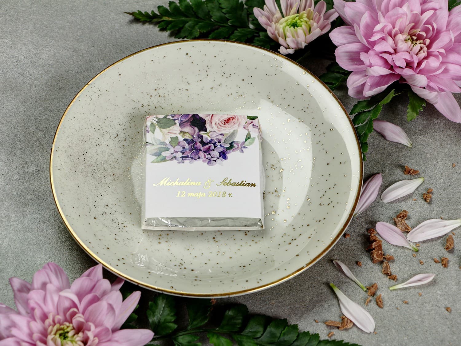 Ringraziamento per ospiti matrimoniali in forma di cioccolatino, incarto con scritte dorate e grafica di rose viola e rosa