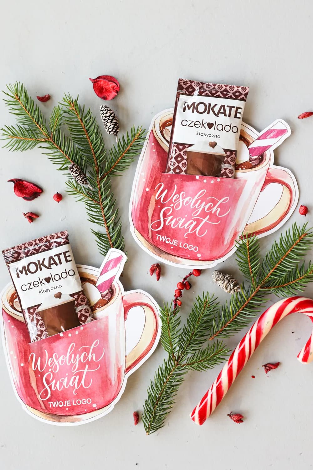 Two corporate Christmas gifts in the form of mugs with Mokate hot chocolate, decorated with spruce branches and logo