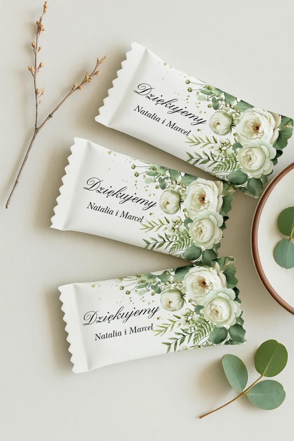 Primer plano de un elegante detalle dulce para invitados con la inscripción 'Gracias' y motivo botánico greenery.