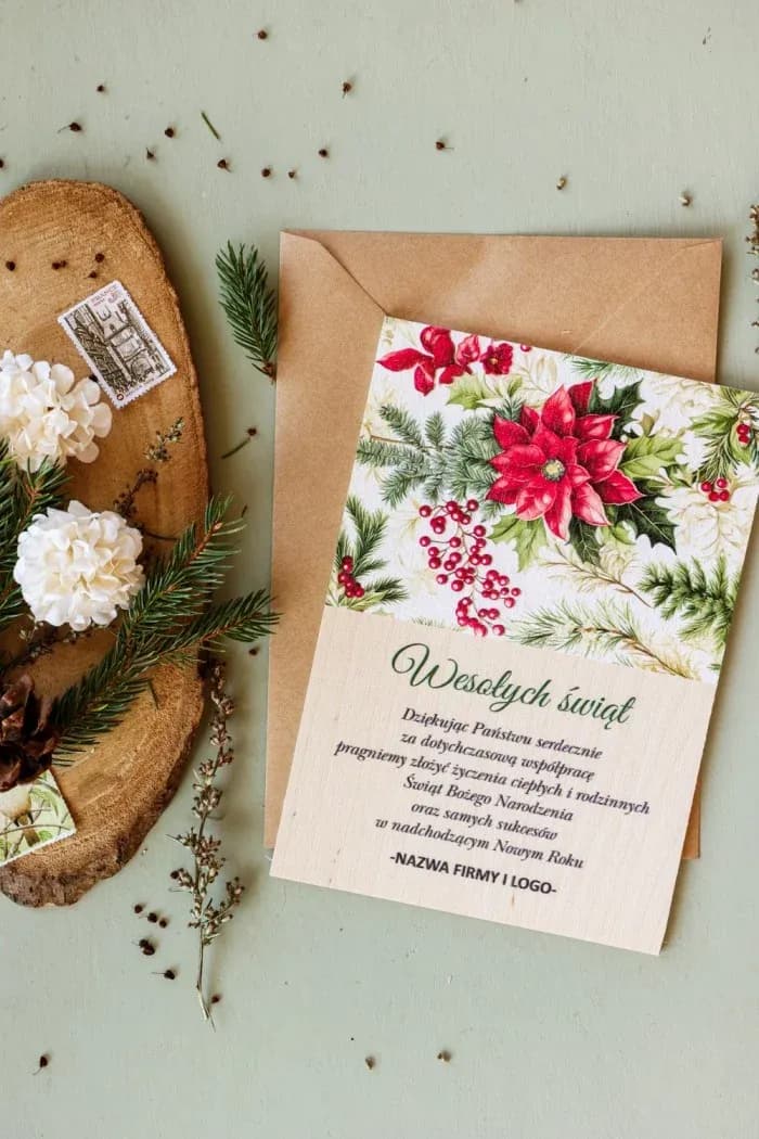 Drewniana kartka świąteczna z grafiką czerwonych kwiatów i zielonych gałązek, personalizowana z logo firmy.