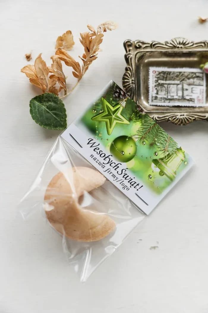 Galleta de la fortuna en envoltorio con diseño de bolas de Navidad verdes de varias formas sobre fondo blanco