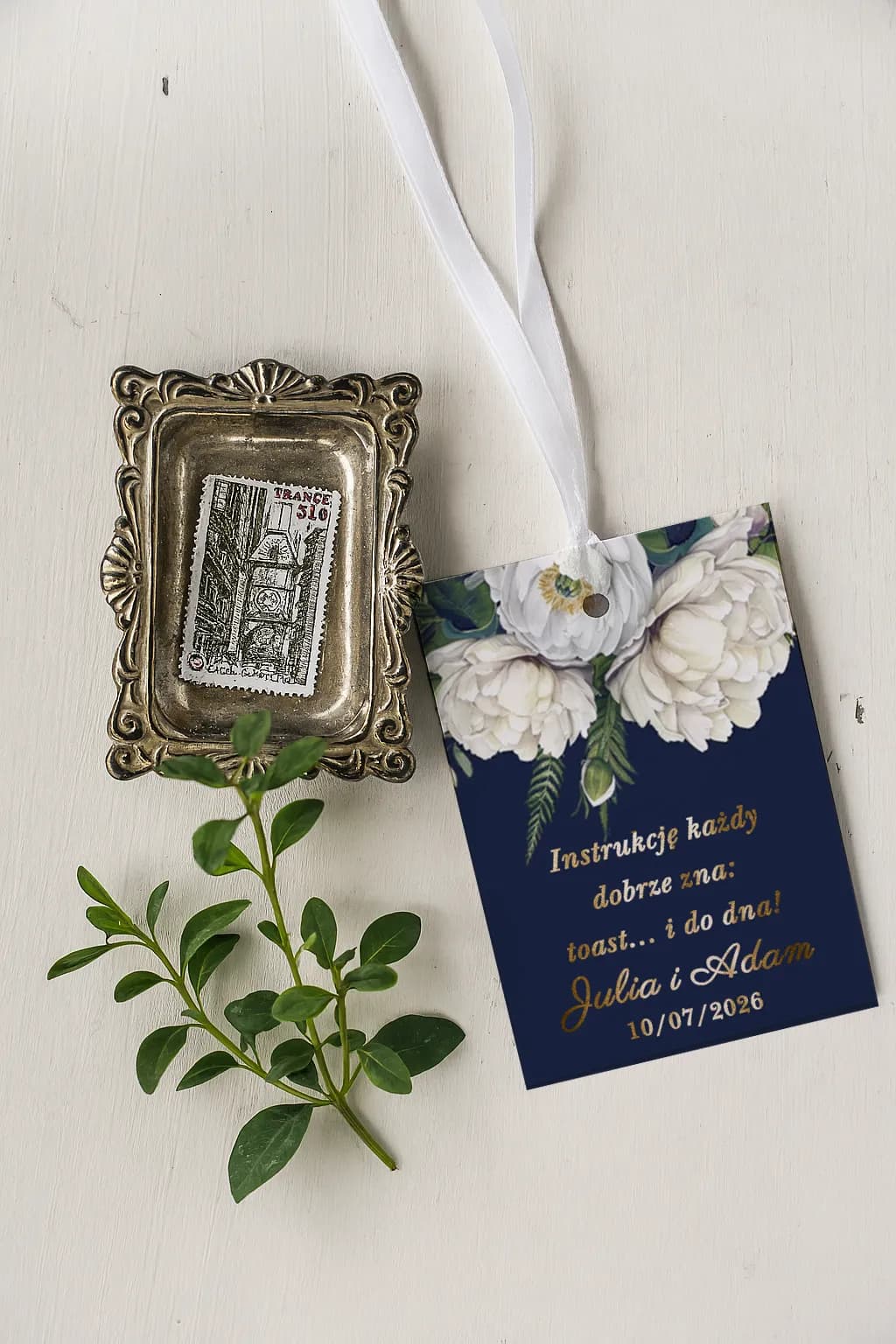 Etiqueta para botella de boda estilo glamour, fondo azul marino, flores blancas y texto dorado para brindis.