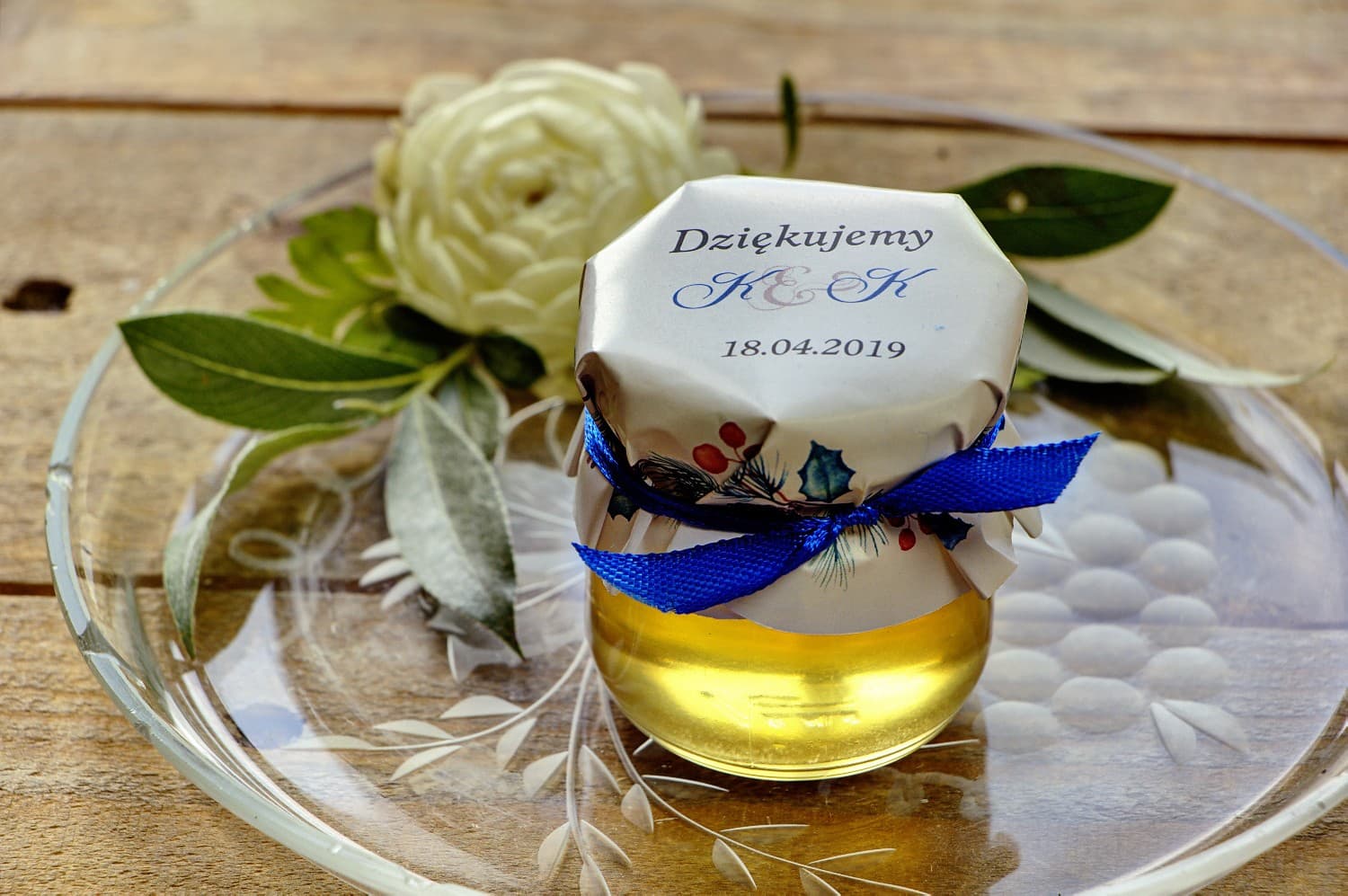 Süße Gastgeschenke zur Hochzeit in Form von Honiggläsern mit winterlicher Komposition aus blauen Nadelzweigen