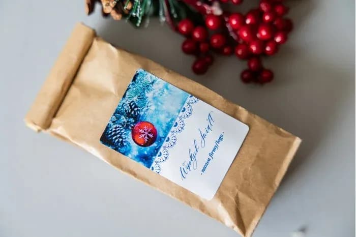 Tea in a kraft bag with a label showing frosted pine branches and a red bauble on a blue background