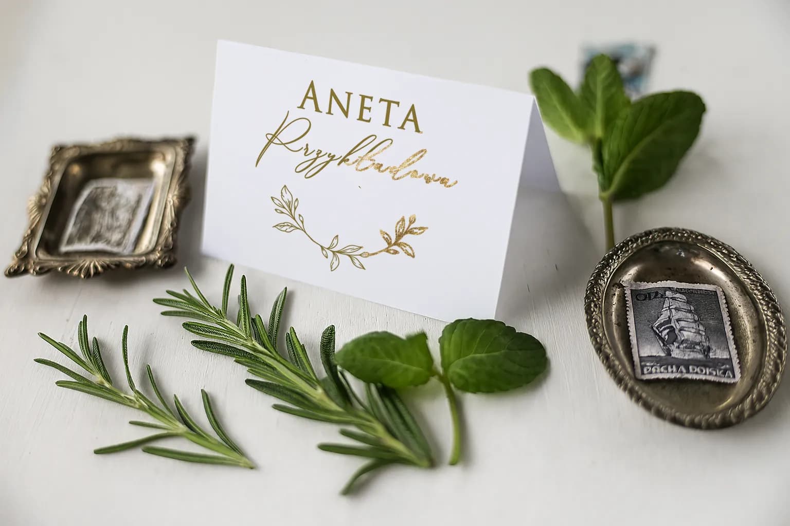 Elegante marcasitios de boda plegable con el nombre del invitado, decorado con un motivo de rama dorada.