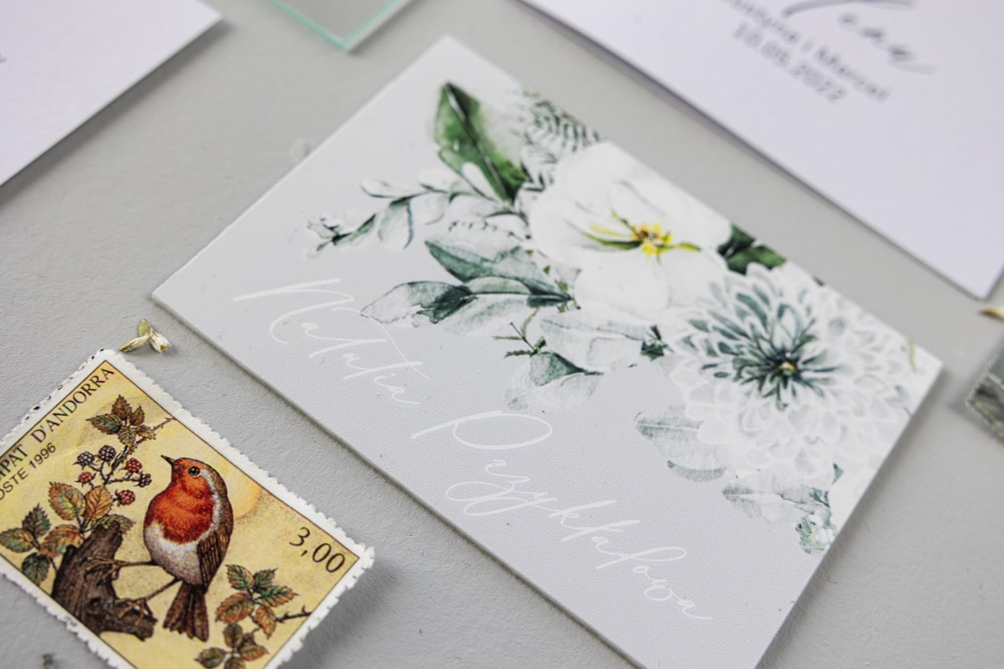 Marque-place en verre motif floral blanc Marque-places de mariage sur verre avec astres et fleurs blanches, bouquet d'eucalyptus et fougère.