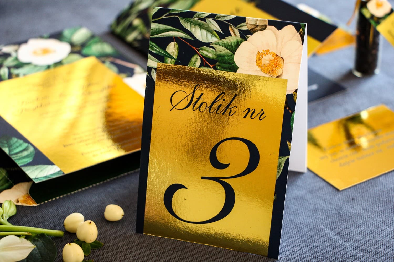 Números de mesa de boda dorados, gráfico azul marino con camelia blanca y hojas verdes