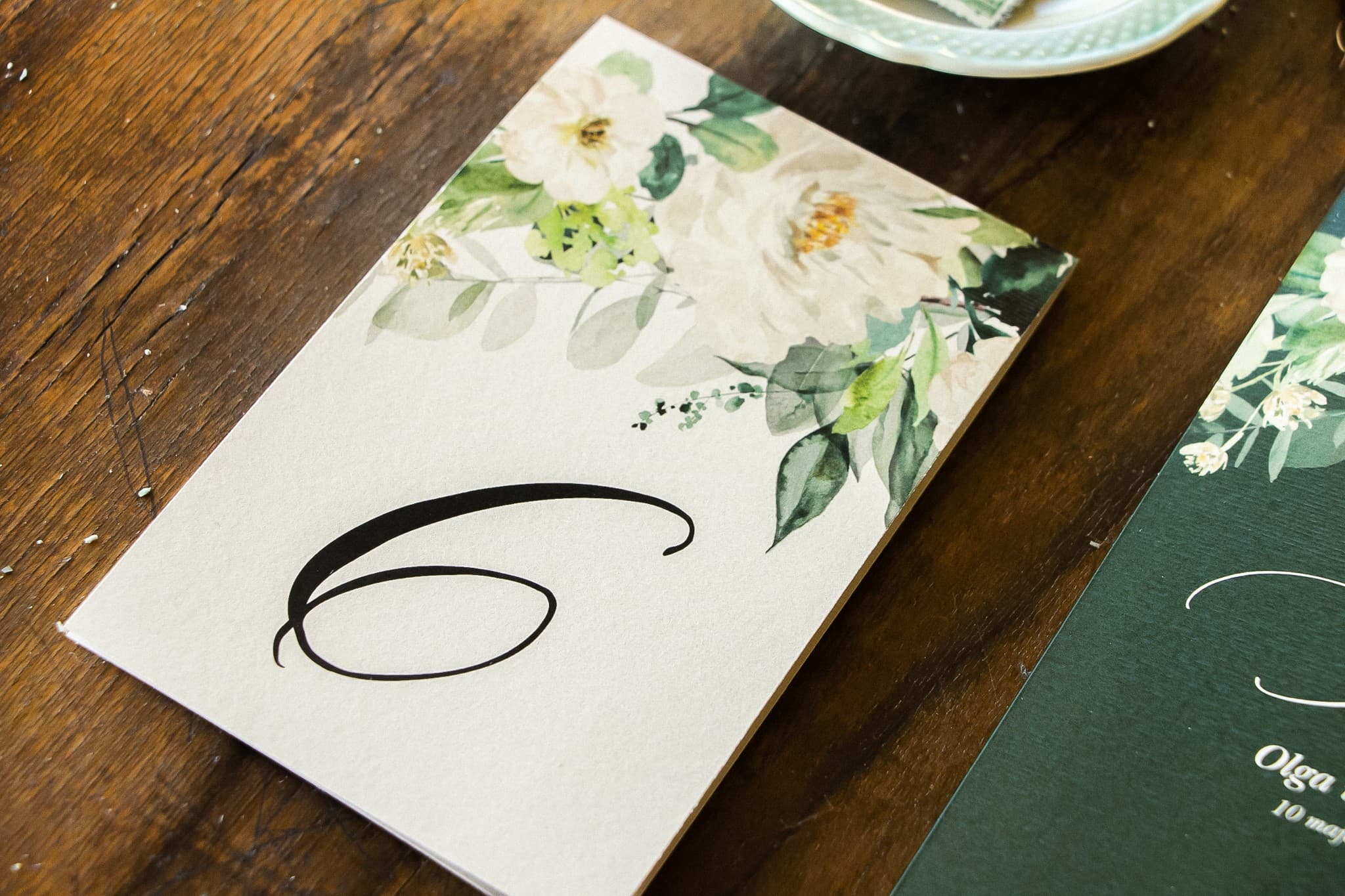 Números de mesa para bodas con flores blancas y ramas decorativas elegantes.