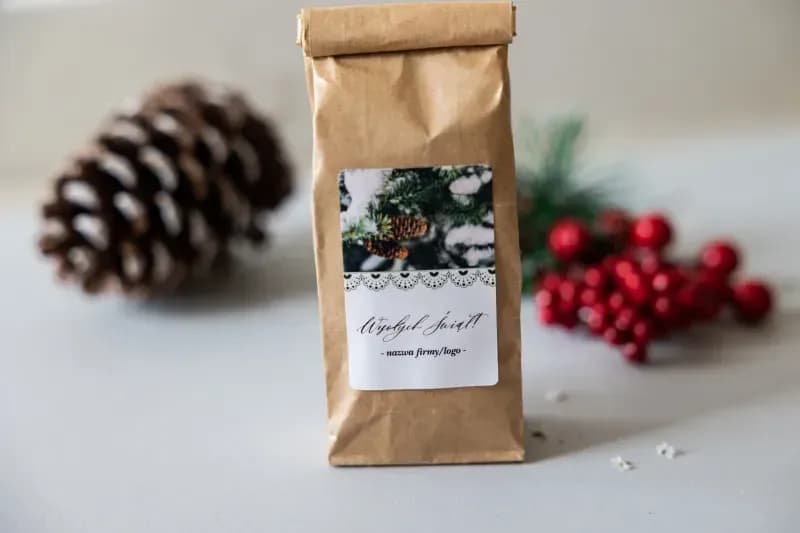 Close-up of a corporate gift label featuring snowy spruce branches, pinecones, and space for a company logo.