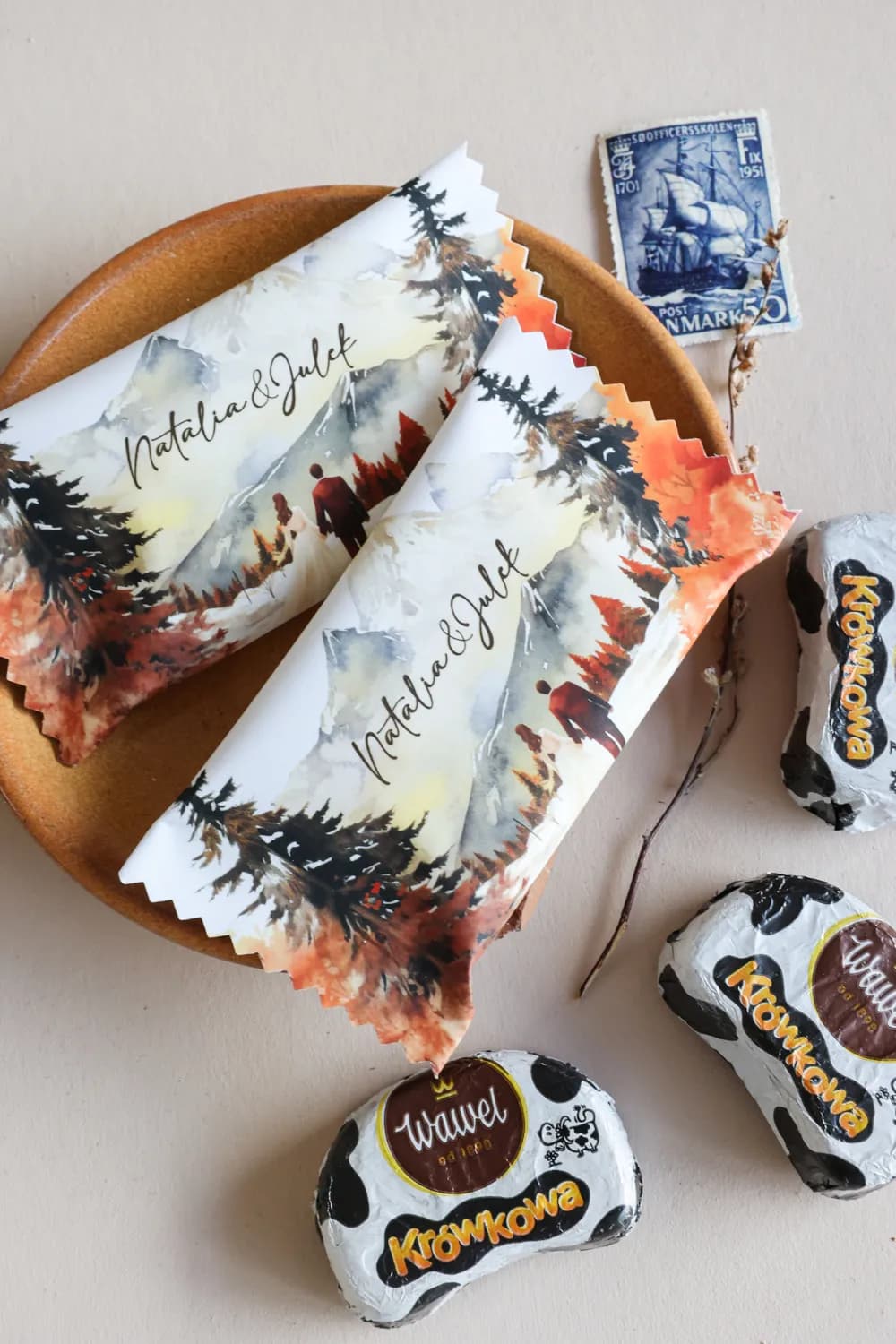 Romantic wedding chocolates with an atmospheric motif of a couple against an autumn forest and mountains in watercolour style.