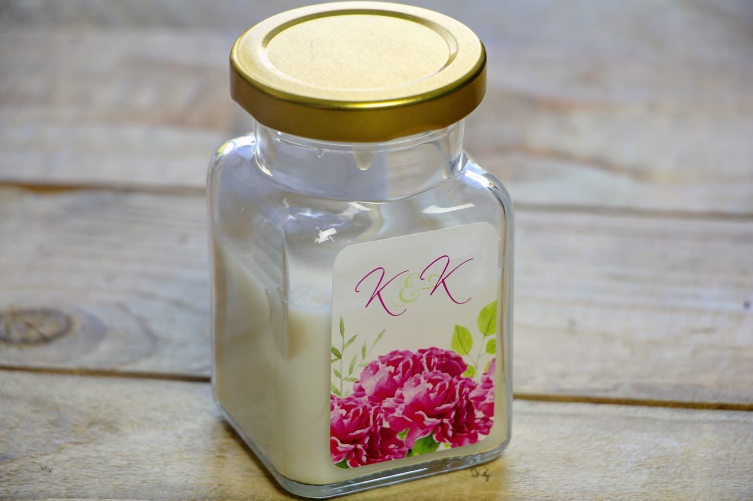 Sojakerzen als Gastgeschenk zur Hochzeit mit intensiv rosa Nelken und grünen Akzenten