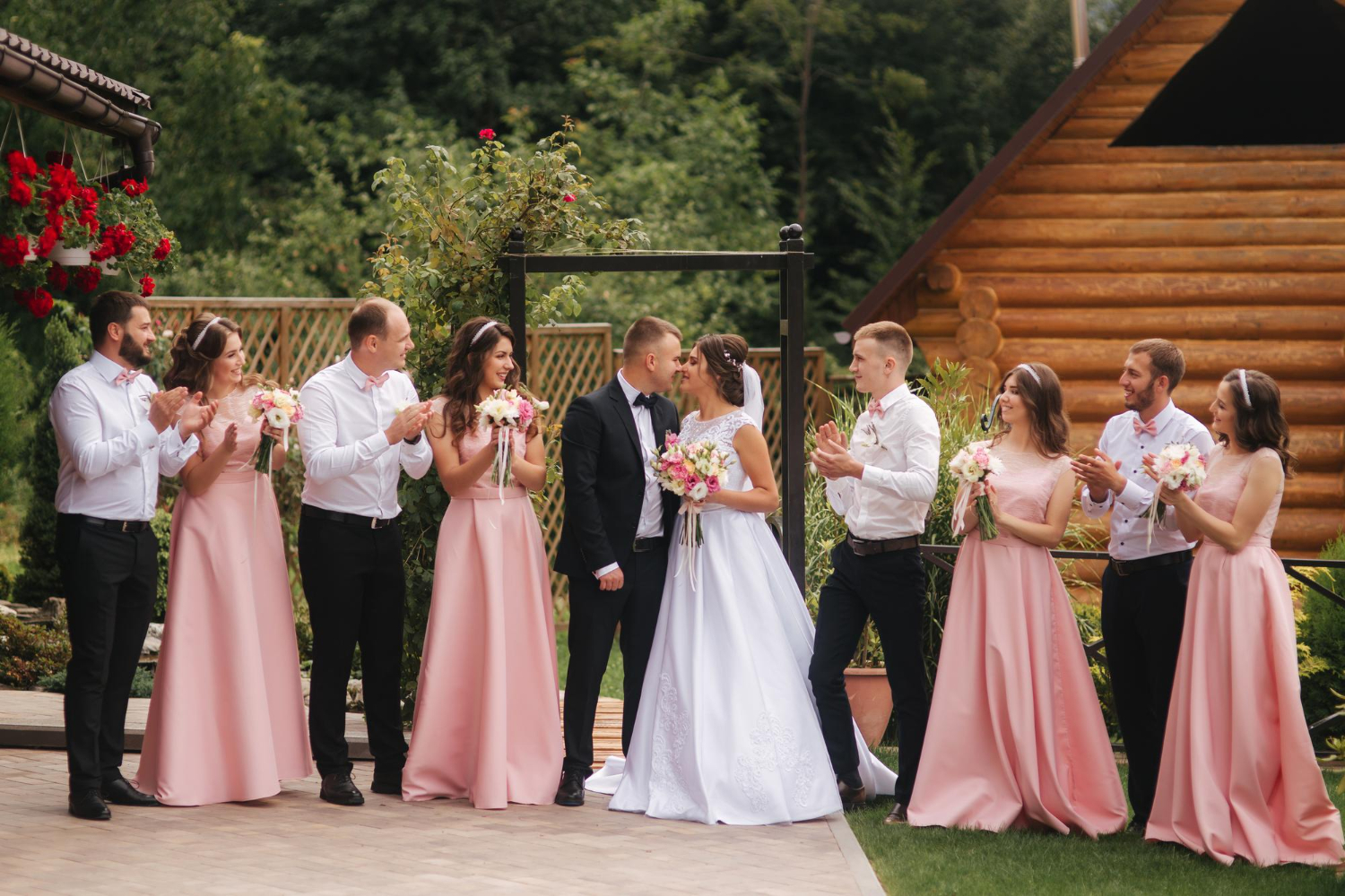 Zdjęcie pan młody i panna młoda stoją z drużbą i druhną na zewnątrz nowożeńcy całują się 